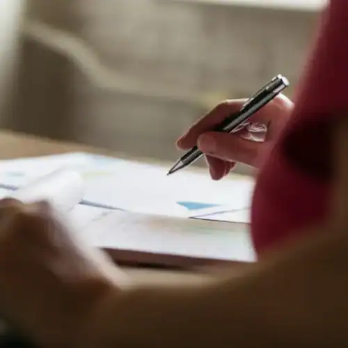 Persona firmando documentos con un bolígrafo sobre una mesa