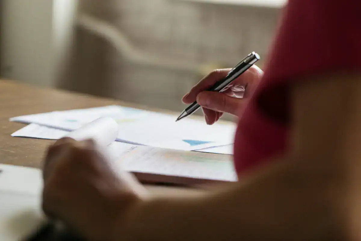 Persona firmando documentos con un bolígrafo sobre una mesa